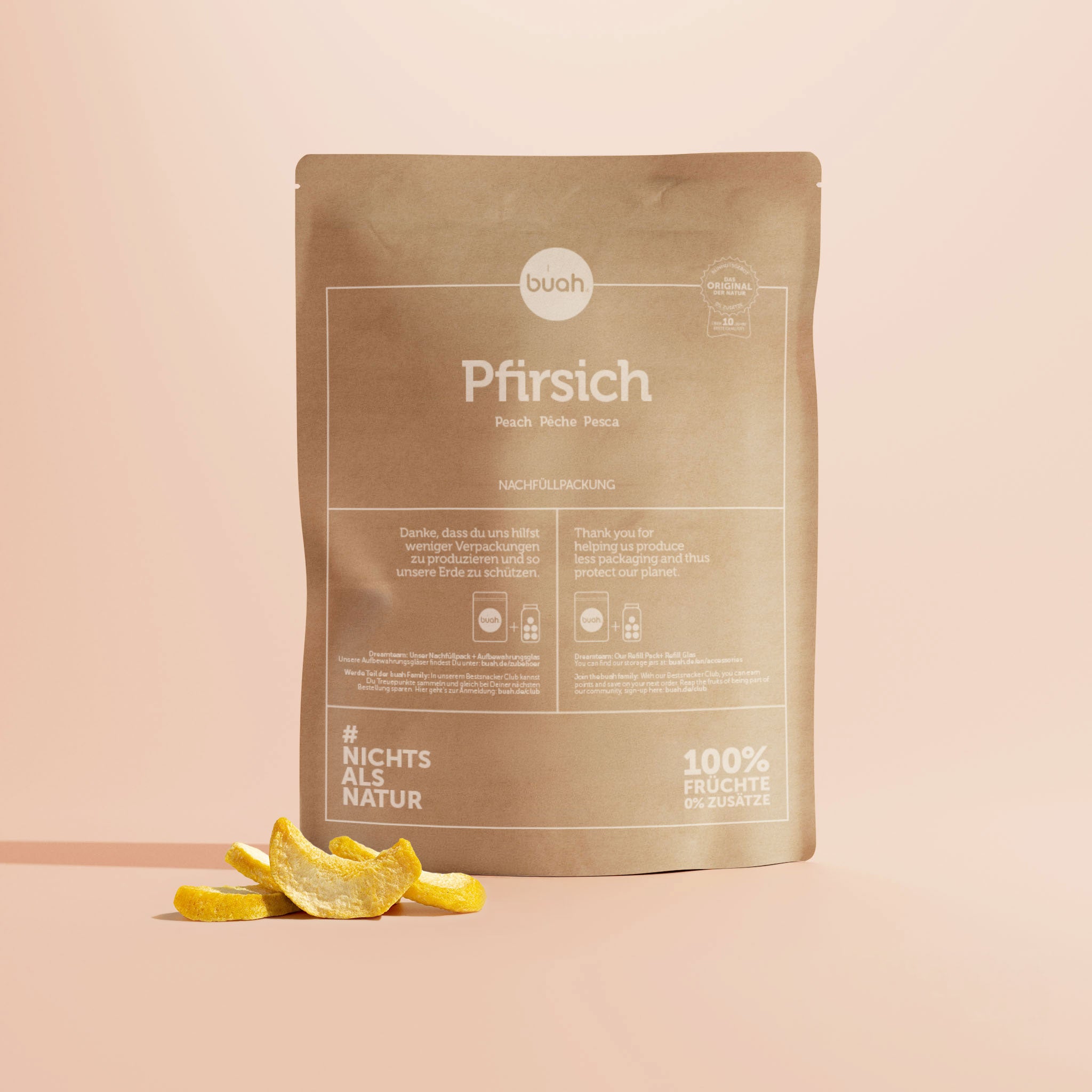 Eine große Nachfüllpackung aus braunem Kraftpapier für buah gefriergetrocknete Pfirsiche steht im Zentrum vor einem beigefarbenen Hintergrund. Davor liegen passend einige knusprige Pfirsichstücke.