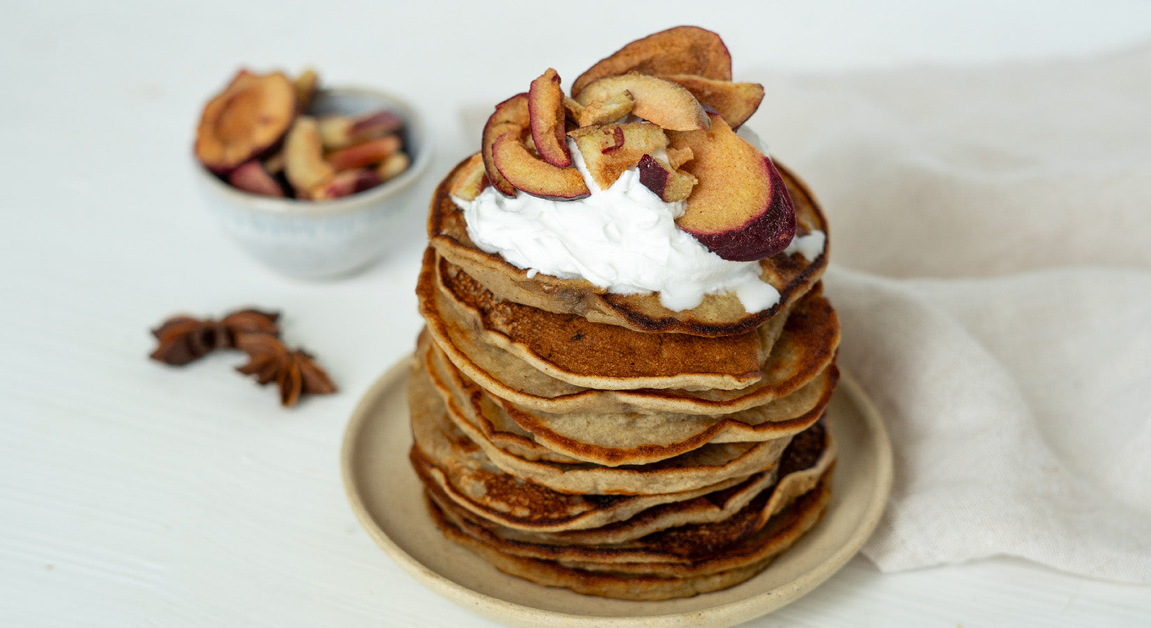 buah Adventskalender Sorte Pflaume als Topping auf gestapelten Pancakes auf einem Teller