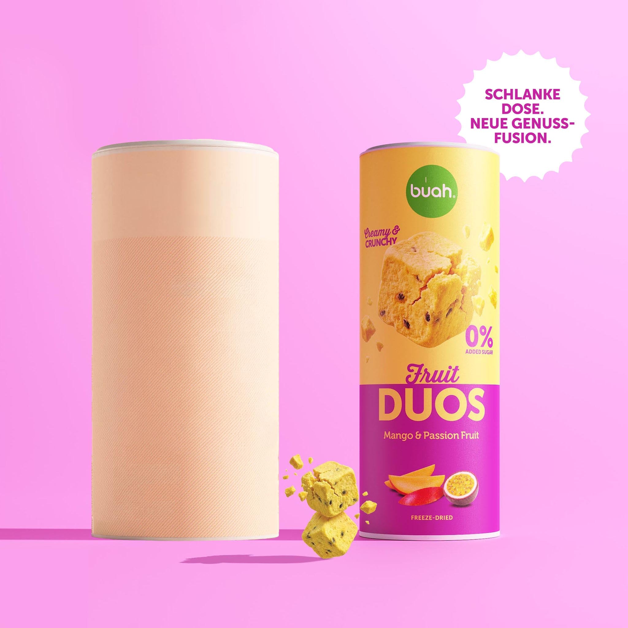 Zwei Dosen stehen als Größenvergleich nebeneinander vor einem pinken Hintergrund. Links eine unbeschriftete große Dose ohne Etikett, vor der ein zerbrochener Fruchtwürfel schwebt. Rechts die schlanke Dose buah Fruit DUOS Mango & Passionsfrucht. Oben rechts ein Badge mit der Aufschrift: „SCHLANKE DOSE. NEUE GENUSSFUSION."