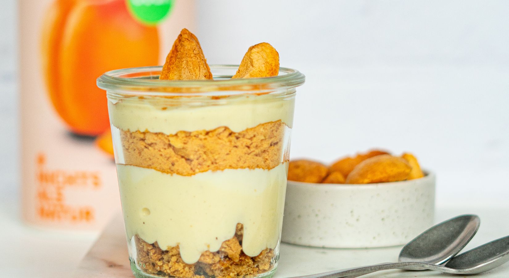 buah Schichtdessert aus Yoghurt und buah Aprikose in einem Glas vor einer Dose buah Aprikose stehend 
