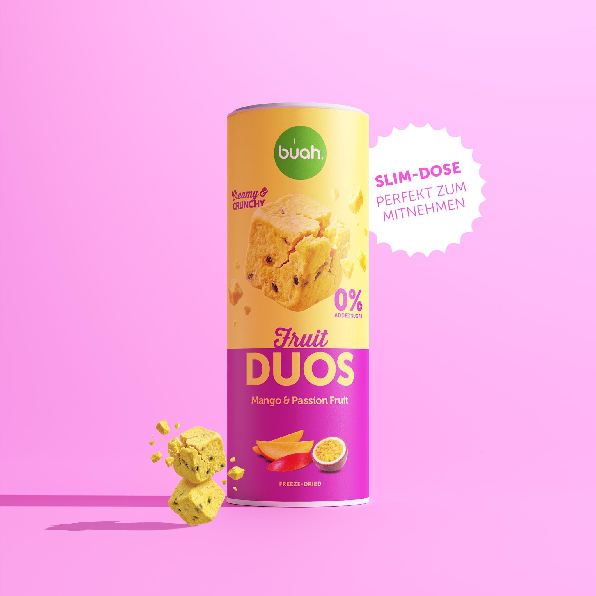 Eine Slim-Dose buah Fruit DUOS Mango & Maracuja steht im Zentrum vor einem rosafarbenen Hintergrund. Daneben steht in einer weißen, gezackten Blase: „SLIM-DOSE PERFEKT ZUM MITNEHMEN“. Links schweben Fruchtwürfel.