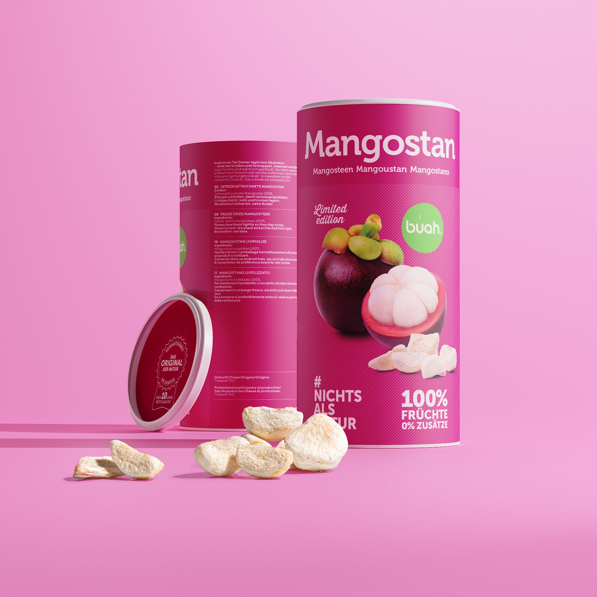 Eine Dose buah gefriergetrocknete Mangostan zeigt ihre Rückseite mit den Zutaten. Der rote Deckel lehnt seitlich an der Dose. Davor liegen helle Fruchtstücke auf einem pinken Hintergrund